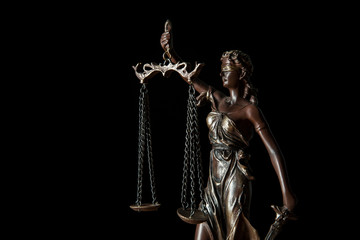 close up of bronze statuette with scales of justice isolated on black