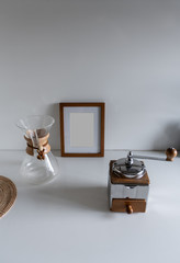 composition of hand coffee grinder in stainless material with drip pot glass in wood collar and wooden frame in the background / space for advertising / object isolated / interior design decoration