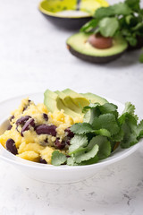 Healthy vegan brunch bowl with  grits, black beans,  avocado