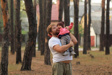 Cuddling father and baby daughter laughing in the park