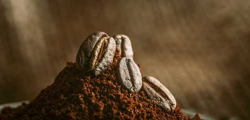 ground coffee poured into the holder on which the grains of roasted, fragrant coffee lie. on the background of fried grains