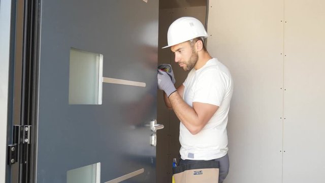 handsome young man installing front door in a new house construction site