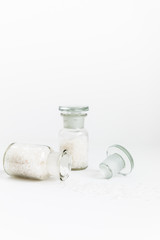 Pure Natural Coarse Sea Salt Spilling Out of A Vial On White Background
