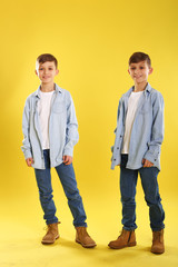 Happy twins on yellow background playing each other 