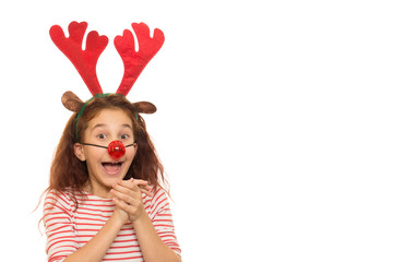 Adorable curly haired young girl wearing Christmas antlers and red nose clapping her hands looking excited isolated copyspace x-mas celebration festive mood family childhood presents holidays