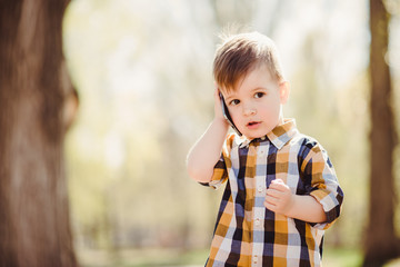 cute boy speaks by mobile phone in the park