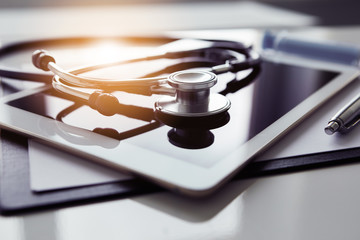 Healthcare and technology concept - tablet and stethoscope on white table - obrazy, fototapety, plakaty