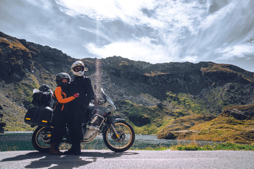 Young couple of motorcycle travelers in the autumn mountains of Romania. Moto tourism and moto travellers lifestyle while traveling Europe