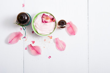 cosmetic cream, tincture, essential oil bottles, with pink flower petals, white wood table