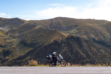 Biker is sitting on his adventure motorcycle, the top mountain in background, enduro, off road, beautiful view, danger road in mountains, freedom, extreme vacation. Transfagarasan Romania