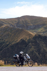 Obraz premium Biker is sitting on his adventure motorcycle, the top mountain in background, enduro, beautiful view, danger road in mountains, freedom, extreme vacation. Transfagarasan Romania, vertical photo