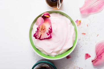 cosmetic cream, tincture, essential oil bottles, with pink flower petals, white wood table