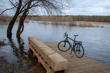 Fototapeta na wymiar Black bike on a wooden bridge near the river