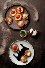 Few puff pastry cups filled by cheese and ham on blue plate with dark sauce