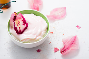 cosmetic cream with pink flower petals, white wood table