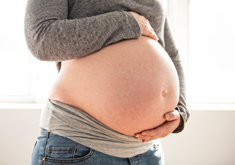 close pregnant woman caressing her belly at home