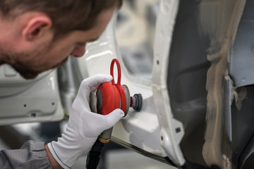 A worker in the painting shop of a car body, sanding painted items