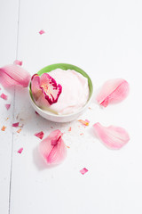 cosmetic cream with pink flower petals, white wood table