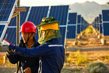 Asian engineer patrolling solar photovoltaic area under the setting sun