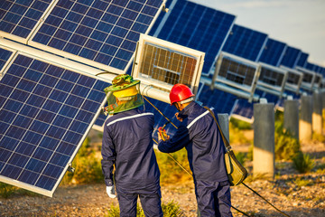 Asian engineer patrolling solar photovoltaic area under the setting sun
