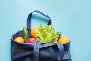 Zero waste concept. Blue shopping textile bag with fresh orange and vegetables. Space for text.