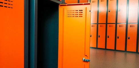 Closeup of locker room situated in work place. Orange lockers, storage for workers.