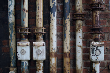 old rusty pipes in front of a brickwall