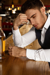 Need to clear his thoughts. Vertical shot of a depressed handsome man drinking at the bar