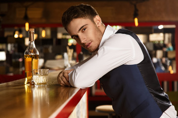 Let me light up your night. Shot of a handsome elegant man looking seductively to the camera having a drink at the bar