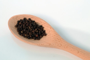 Black pepper in wooden spoon.