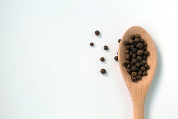 Black pepper in wooden spoon.