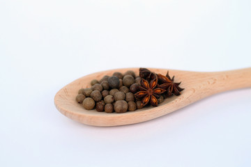 Black pepper in wooden spoon isolated on white.