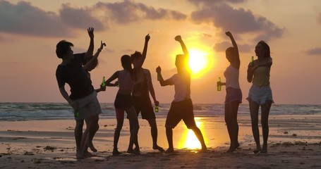 Slow motion of silhouette group of young people dancing at beach party on sunset.