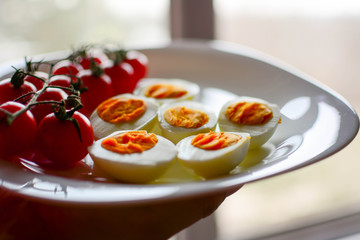 Cooked eggs cut in half with white  bread and cherry tomato on white plate. White plate with healthy food.