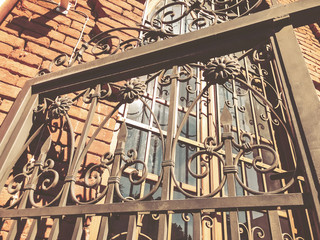 Old Tbilisi architecture in the street. Beautiful iron gate against the bricks wall in summer day