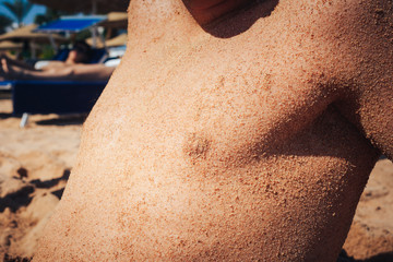 The body of a young guy sprawled in the sand, on the beach by the sea.