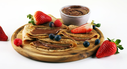 Delicious Tasty Homemade crepes with chocolate or pancakes with raspberries and blueberries on rustic wood