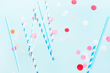 Flying Colorful drinking straws for beverage and colored confetti on a bright background. Birthday festive party cheerful background.