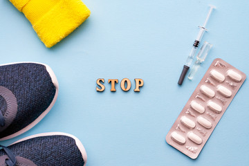 The concept of doping in sport. Inscription stop on a blue background. Sports shoes, pills, syringe...