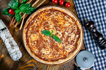Top view on homemade italian pizza with bolognese. Pizza on rustic wooden background with tomato, salami, basilic. Copy space. Traditional italian cuisine. Flat lay picture for recipe or menu