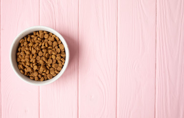 Cat food in bowl on pink wooden background