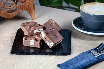 Close up view on homemade chocolate Fudge (sugar candy) with coffee on wooden table. Fresh sweet bakery with copy space. Sweet dessert for cooking book or recipe