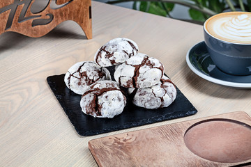 Close up view on homemade chocolate cookies on black chalkboard with coffee. Trending cake with copy space for design. Sweet dessert for cooking book or recipe