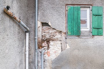 Eine beschädigte Hausmauer und abgeplatzter Außenputz mit einem großen Loch, Deutschland