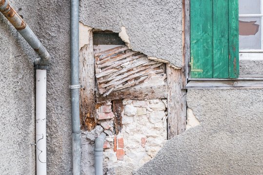 Eine besch&auml;digte Hausmauer und abgeplatzter Au&szlig;enputz mit einem gro&szlig;en Loch, Deutschland