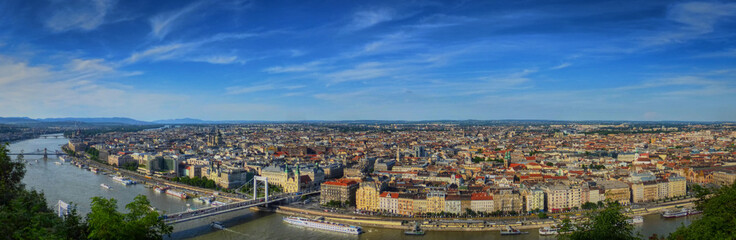 Obraz premium A panoramic view of the eastern half of Budapest (Pest) with the Danube river, a few bridges, and lots of boats and buildings