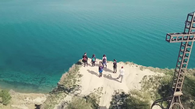 Vista aerea della croce di ferro fissata in cima alla falesia a picco sul mare cristallino nel parco san Bartolo a pesaro. Si vedono anche alcune persone che osservano con cautela il bellissimo panora