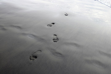 Footprints from the feet of a woman or man on the sand of the beach.