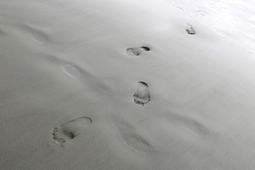 Footprints from the feet of a woman or man on the sand of the beach.