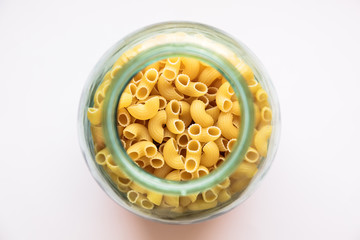 Horns pasta isolated on white background, top view, in glass jar